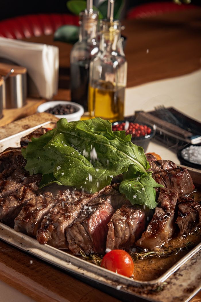 Juicy grilled beef steak topped with fresh greens and cherry tomatoes, perfect for a gourmet meal.